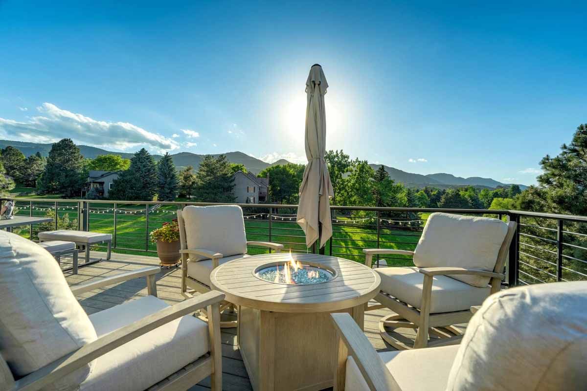 Sunny patio with white chairs and a table overlooking a green landscape and blue sky