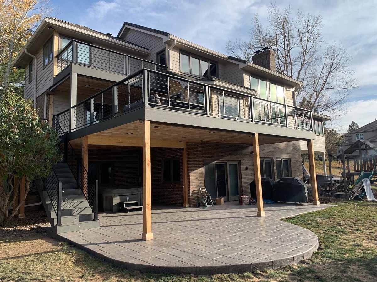 Modern two-story house with a raised deck and covered patio on a landscaped yard