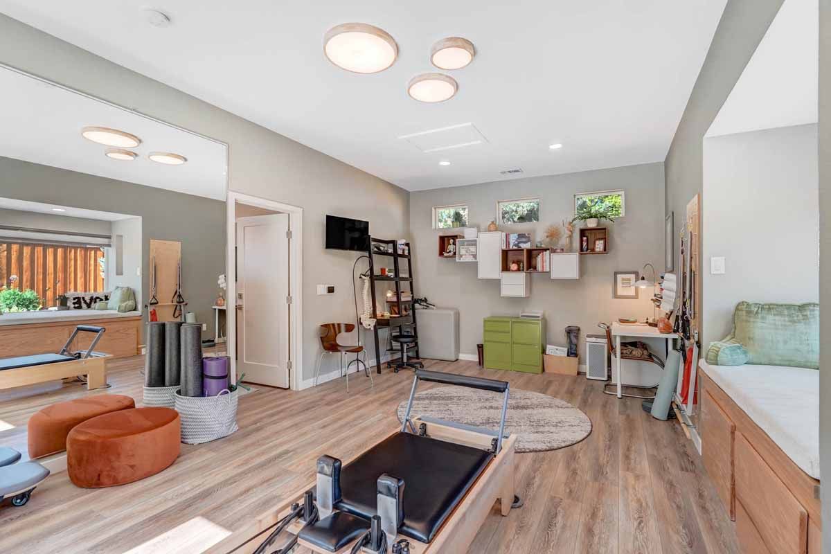Bright yoga studio with mats, props, wall shelves, and large mirror in a spacious room