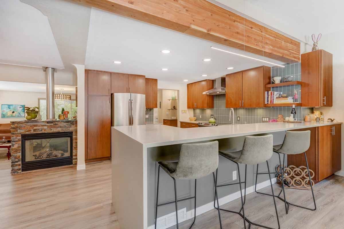 Modern kitchen with wood cabinets, white island, bar stools, and stainless steel appliances