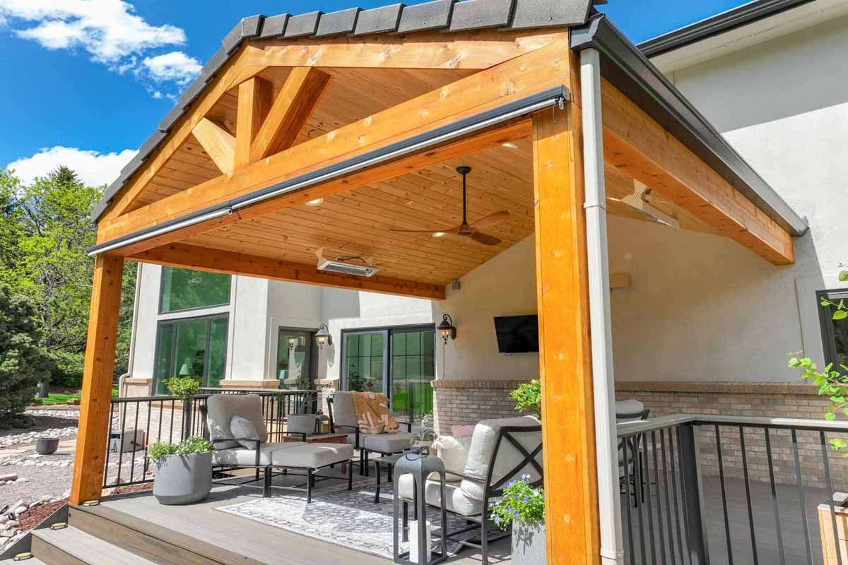 Wooden covered patio with outdoor dining furniture beside a modern house