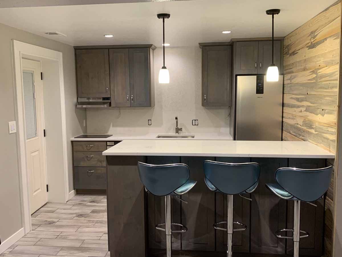 Modern kitchen with dark cabinets, white island, blue bar stools, and pendant lights