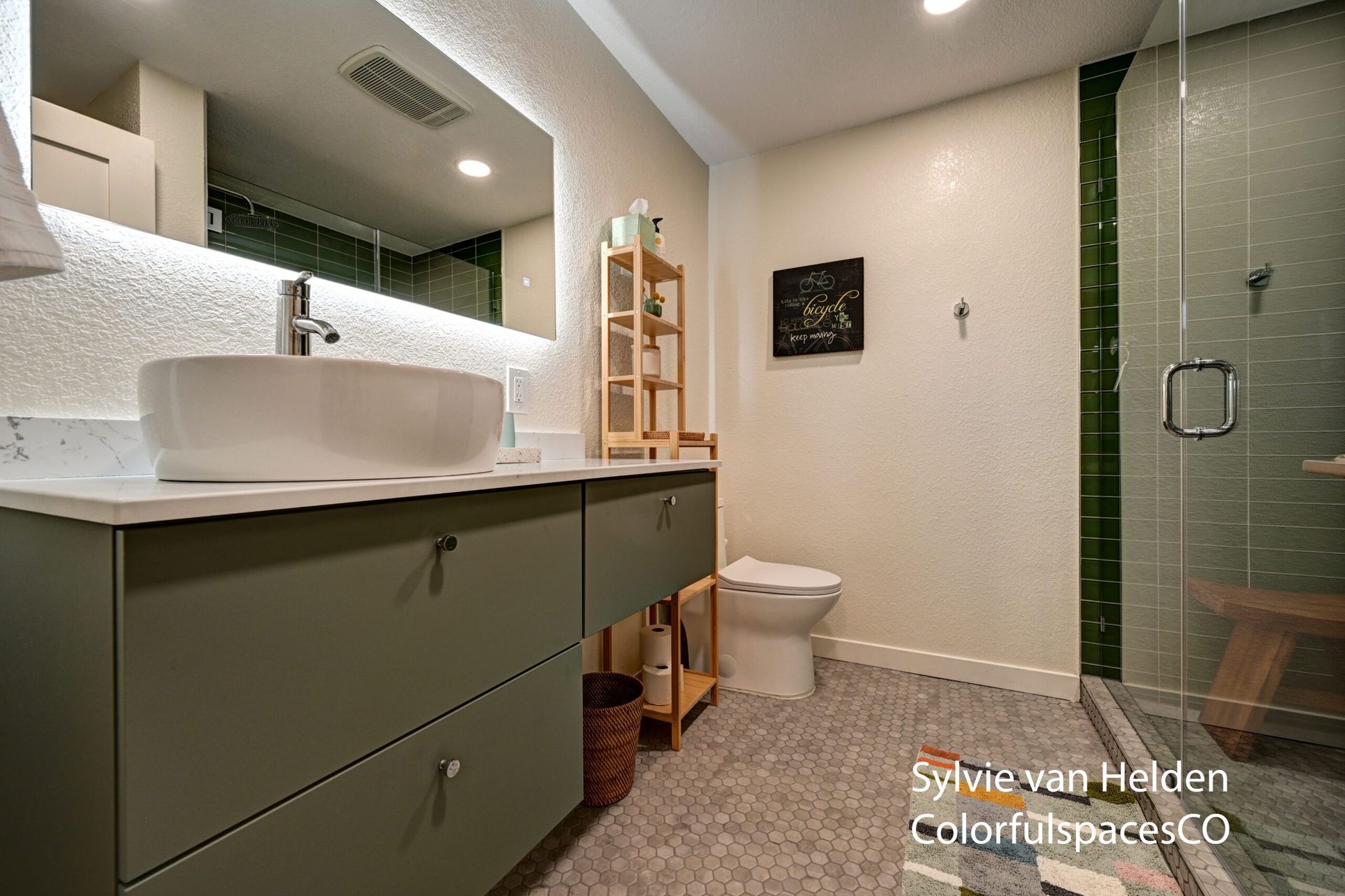 Modern bathroom with green vanity, white sink, toilet, and glass shower enclosure