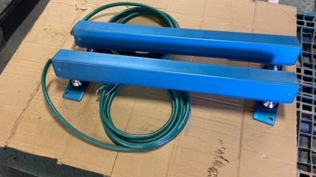 A pair of blue bars with green wires attached to them are sitting on top of a cardboard box.