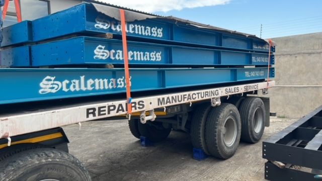 A truck is carrying a stack of scales on the back of it.