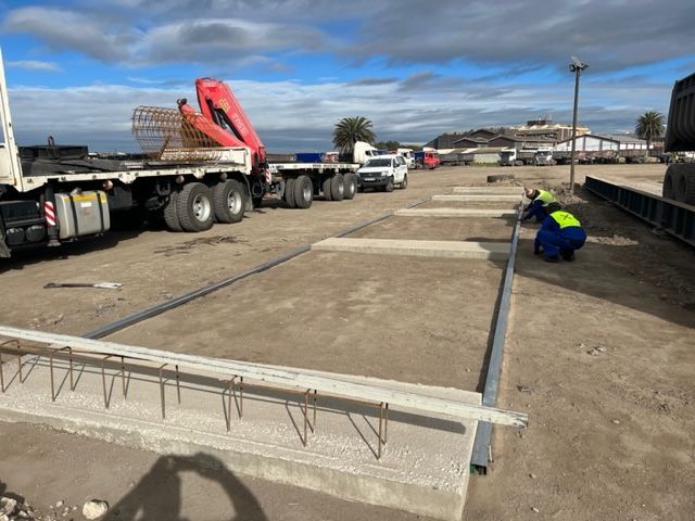 A man is kneeling in the dirt next to a truck.