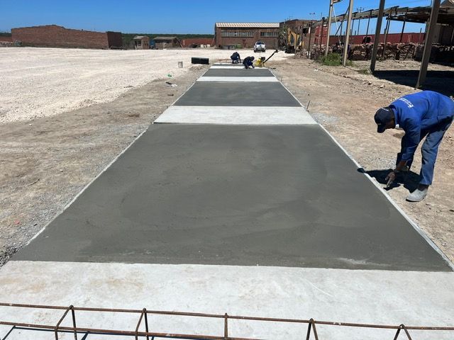 A man in a blue shirt is working on a concrete walkway