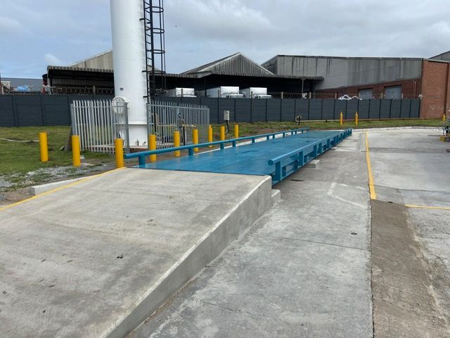 A large blue scale is in a parking lot in front of a building.