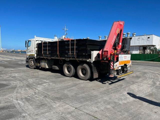 A dump truck with a red crane is parked on the side of the road.