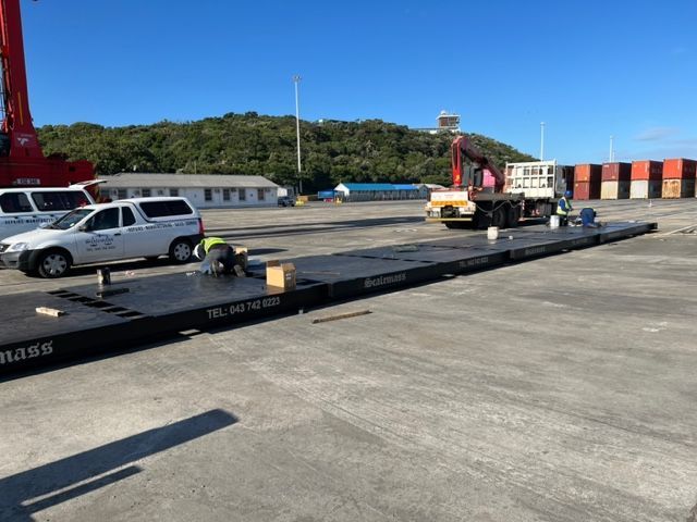 A truck is sitting on top of a large scale in a parking lot.