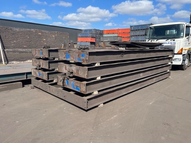 A truck is parked next to a pile of metal beams.