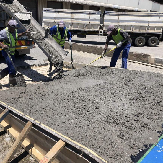 A group of construction workers are working on a large pile of concrete