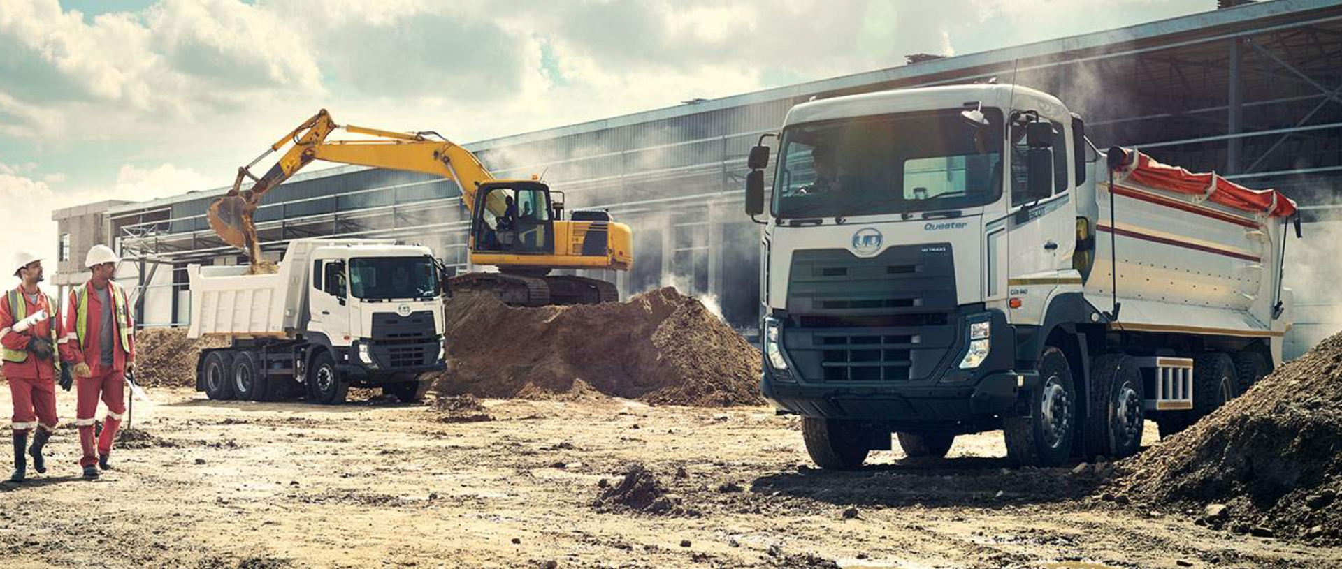 A group of construction workers are standing next to a dump truck on a construction site.