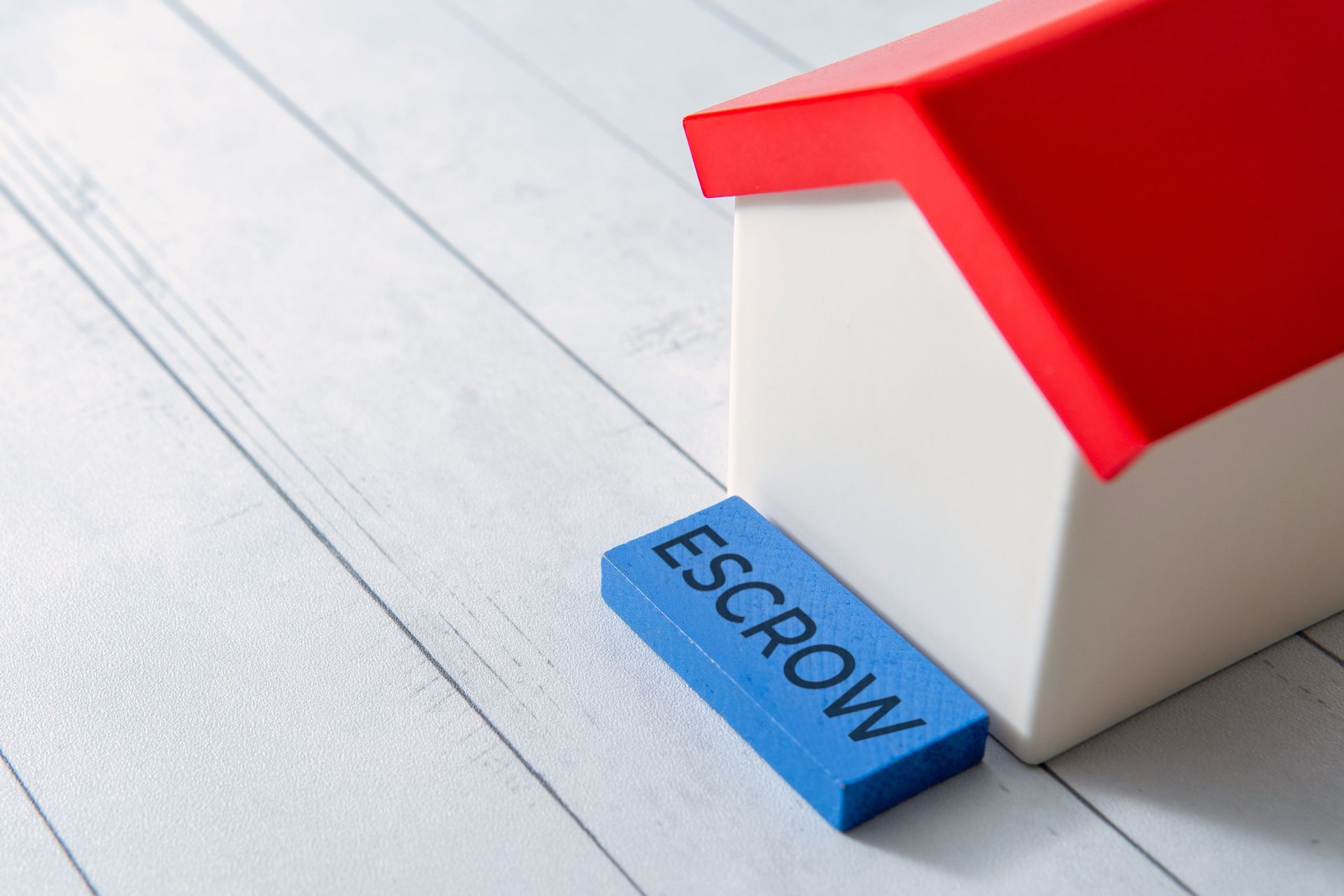 Escrow company concept with toy house and word escrow representing secure real estate deals.