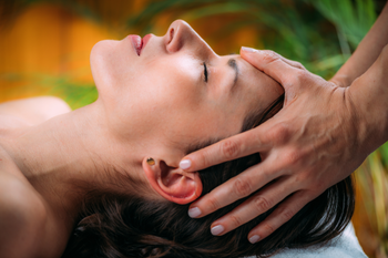 Person receiving a head massage in a spa, eyes closed, with hands cradling the head