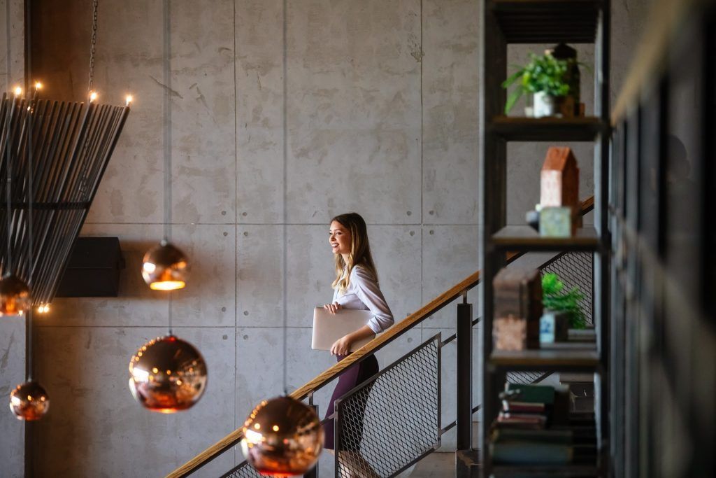 A woman is walking down a set of stairs holding a laptop.