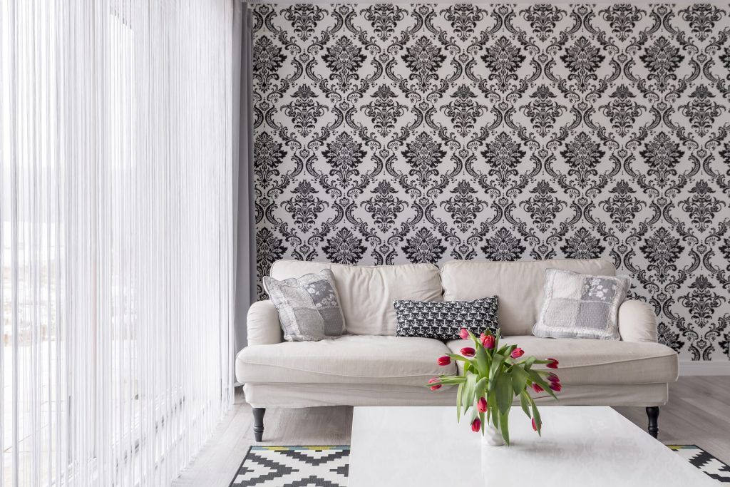 A living room with a white couch and a black and white wallpaper.