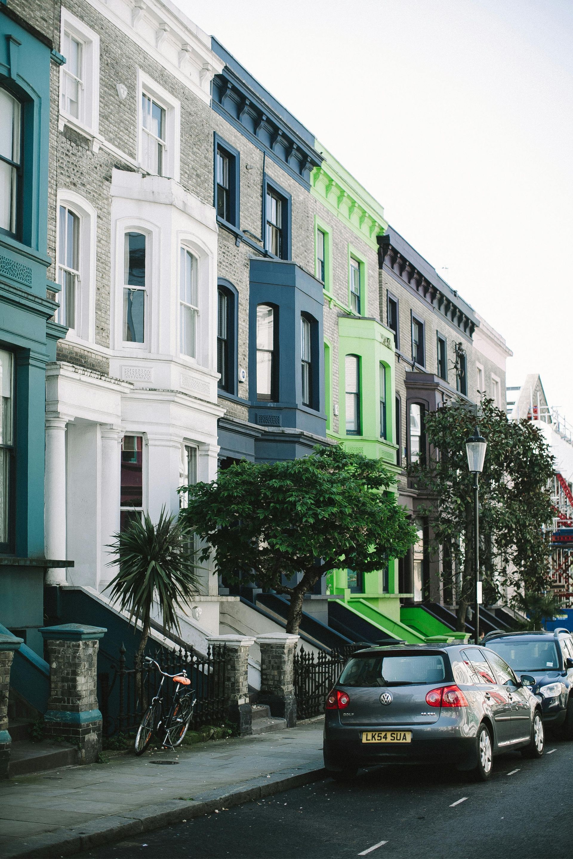 A car is parked in front of a row of colorful buildings.