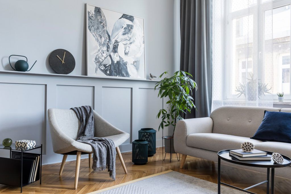 A living room with a couch , chair , coffee table and painting on the wall.