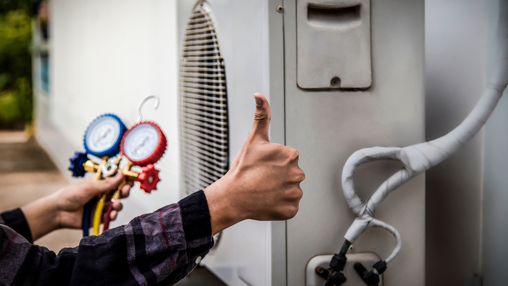 A person is giving a thumbs up while working on an air conditioner.