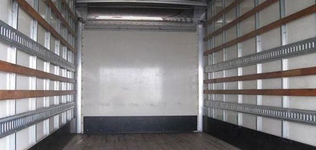 Rolling Doors inside of a trailer with wooden slats on the walls .