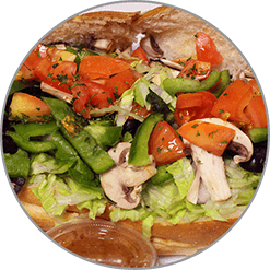 A sandwich with tomatoes , lettuce , mushrooms and olives on a plate.