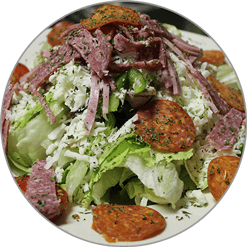 A salad with lettuce , meat , cheese and tomatoes on a plate.