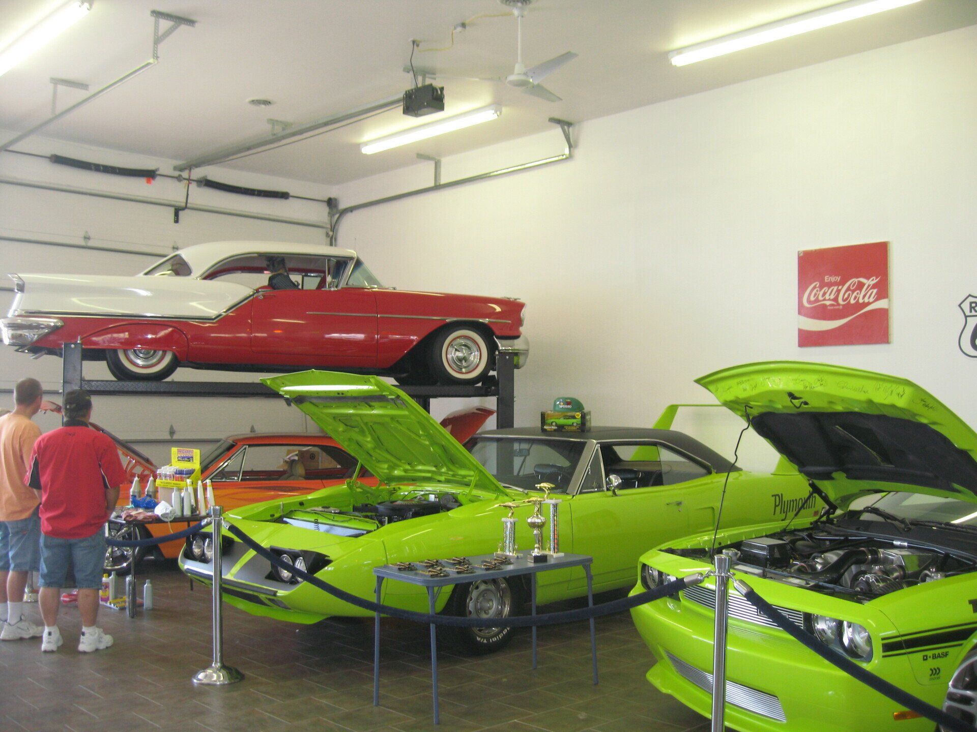 a coca cola sign hangs above a garage full of cars