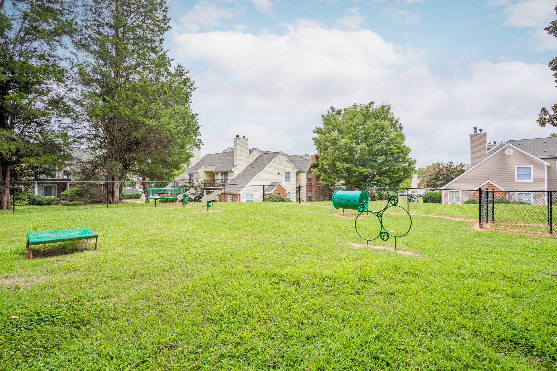 There is a dog park in the middle of a lush green field.