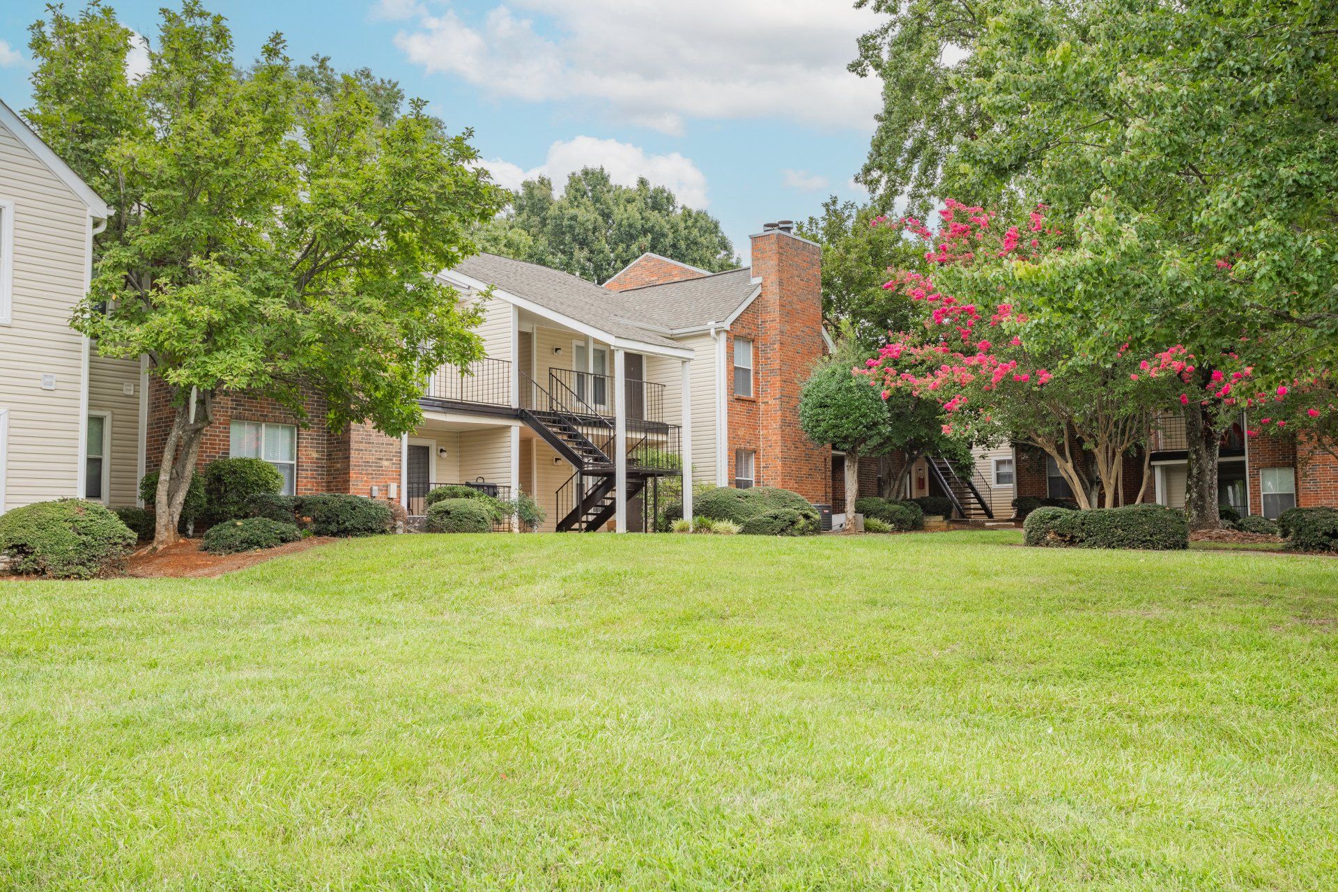 A large lush green lawn in front of a brick apartment building.