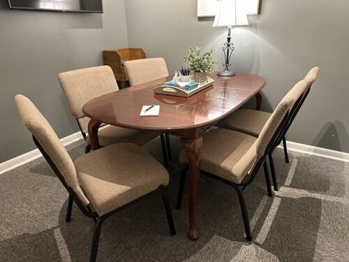 A dining table with four chairs in a room with a lamp and carpet.