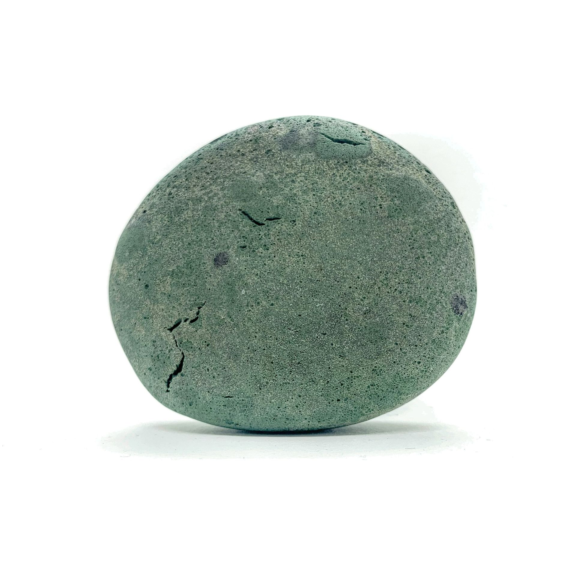 Green, oval-shaped stone with rough texture and a few small cracks, against a white background.