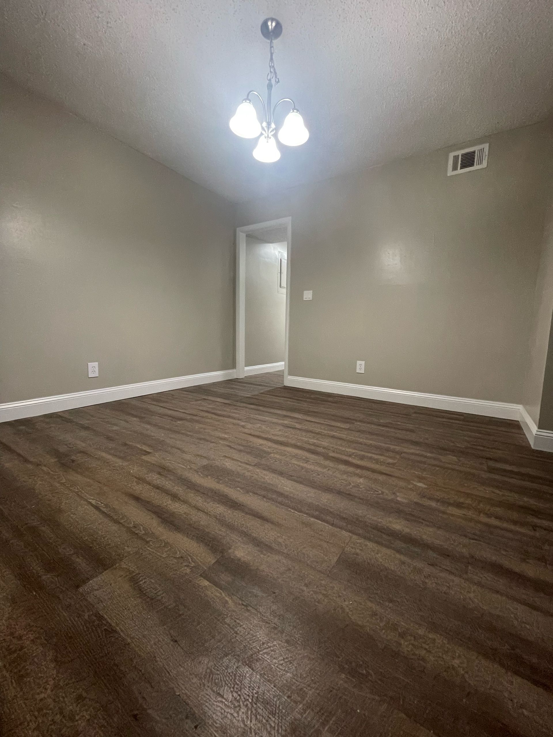 an empty room with a chandelier hanging from the ceiling