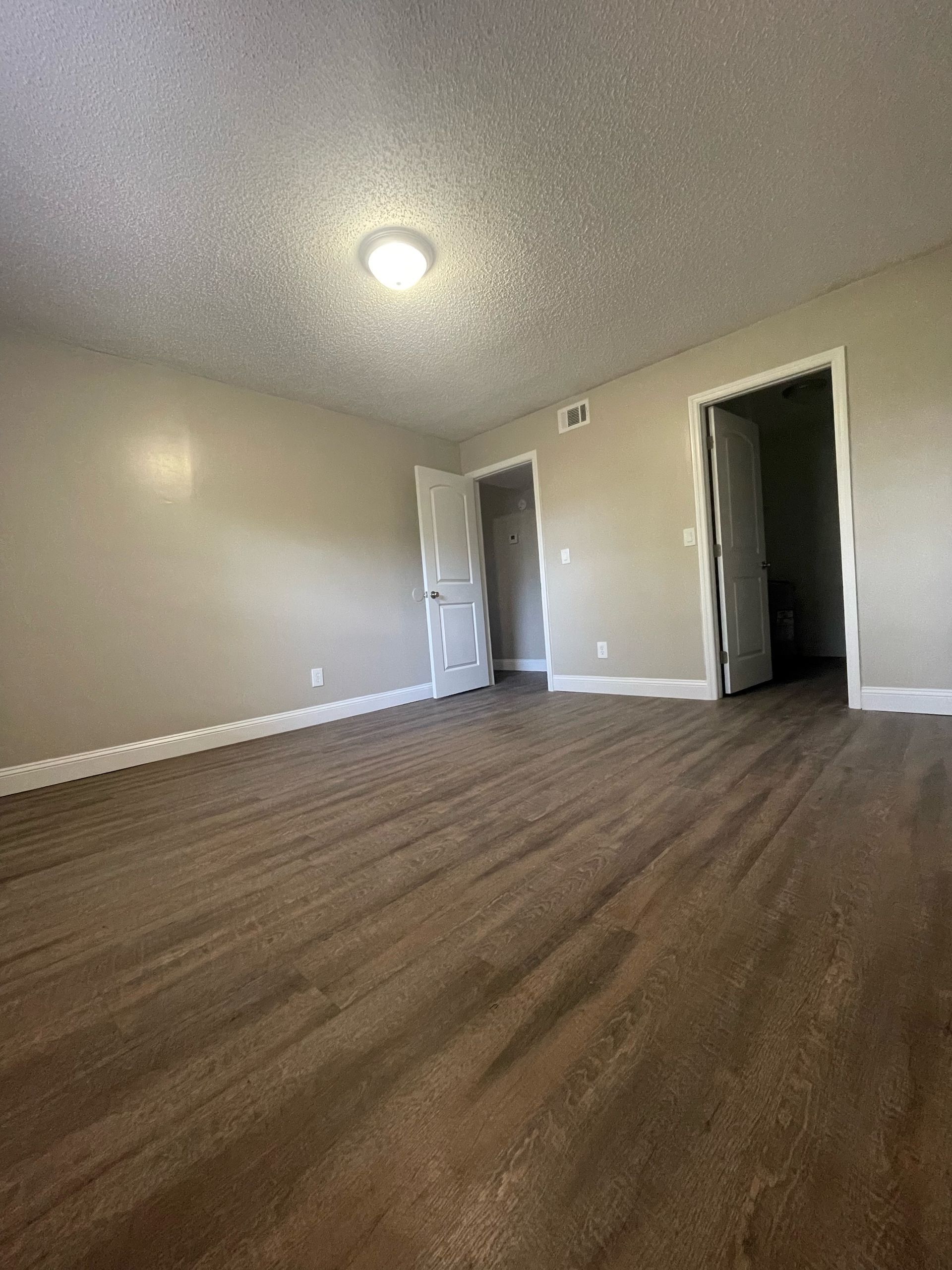 an empty room with hardwood floors and a light on the ceiling