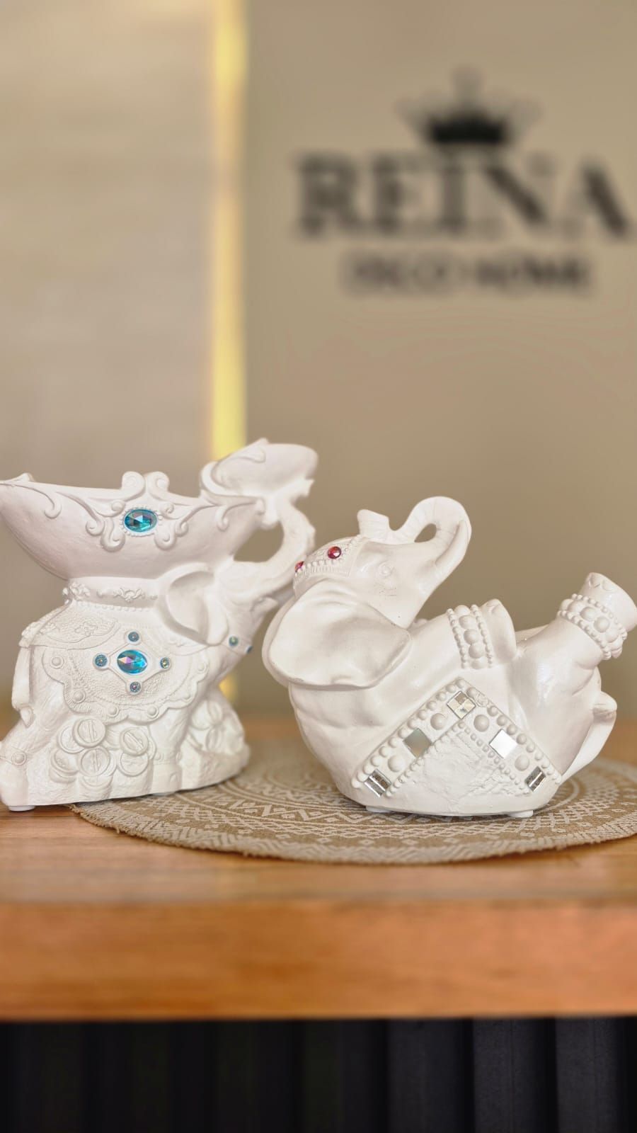 Dos figuritas de elefantes blancos sobre una estera tejida, con un letrero borroso que dice 
