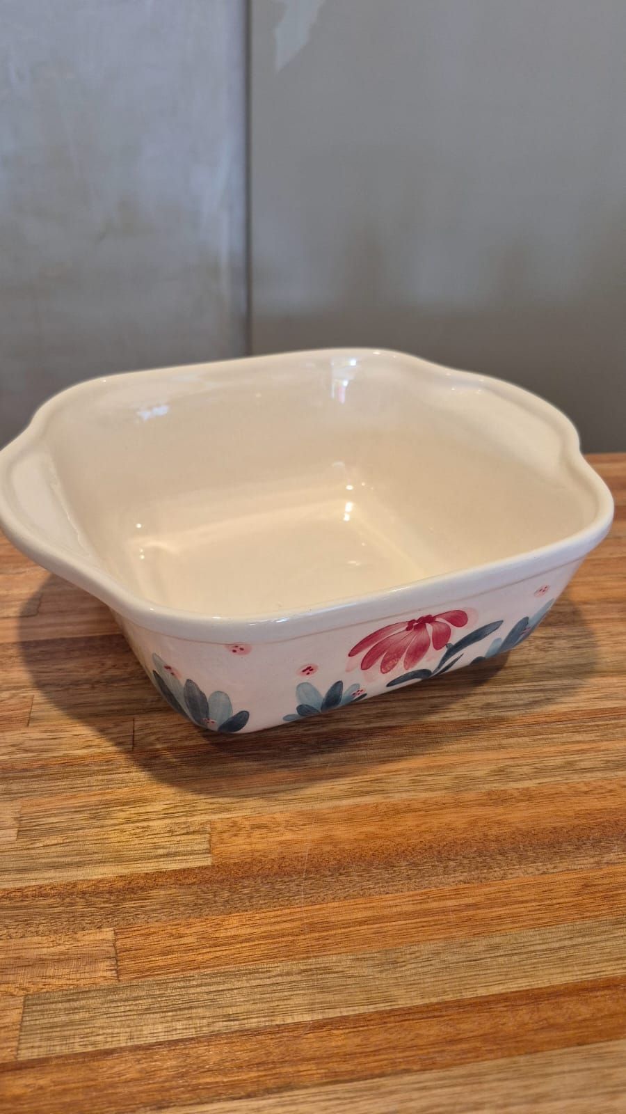 Un pequeño cuenco de cerámica color crema con laterales a rayas azules sobre una mesa de madera.