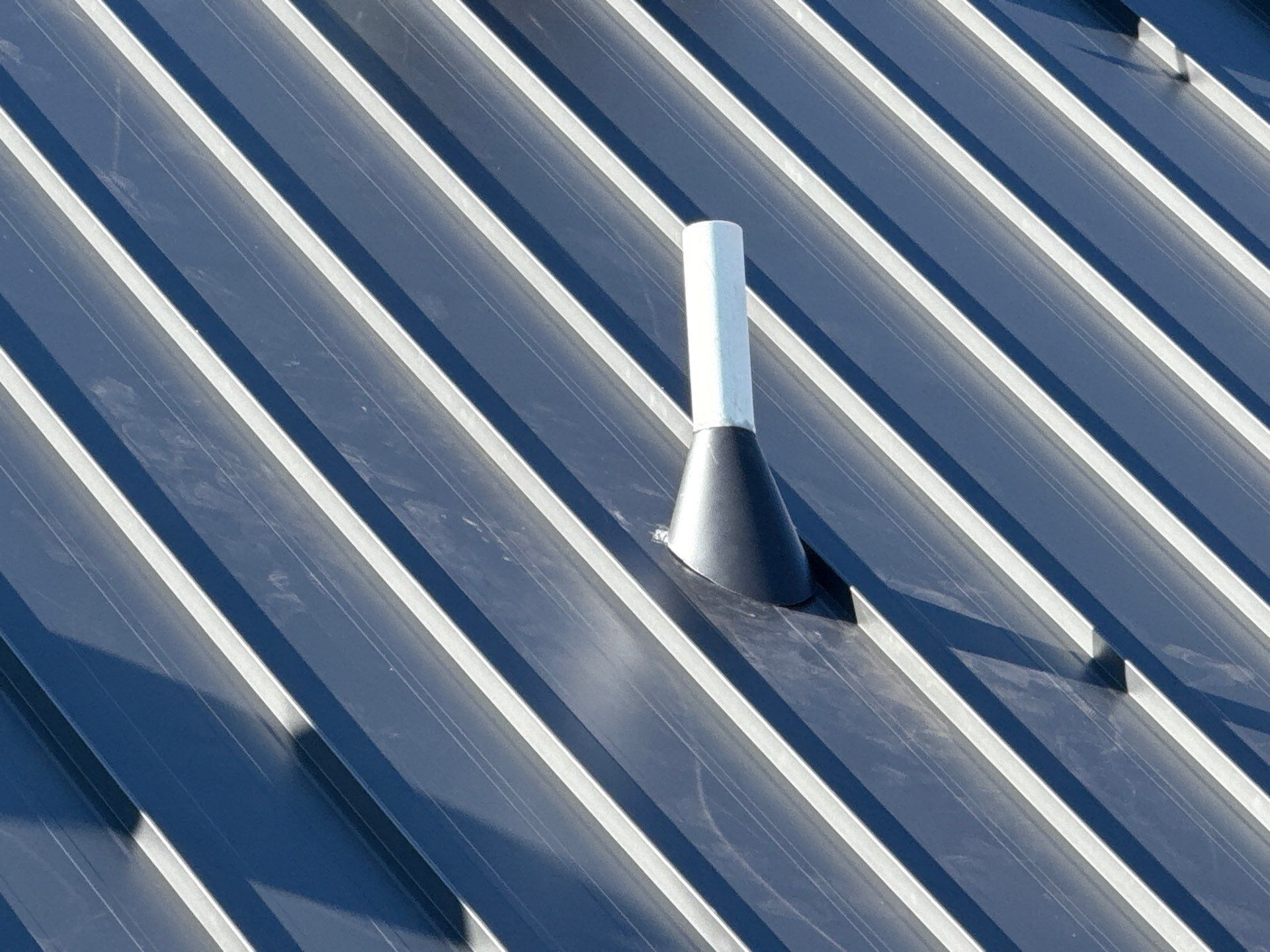Dark metal roof with a black and white vent.