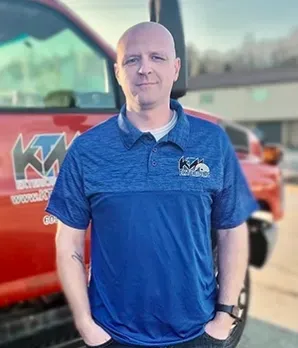 Man in blue shirt, standing in front of red truck with logo.