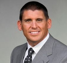 Man in gray suit, smiling, wearing tie.