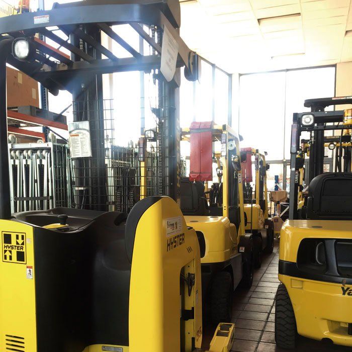 Una fila de carretillas elevadoras amarillas están alineadas en un almacén.