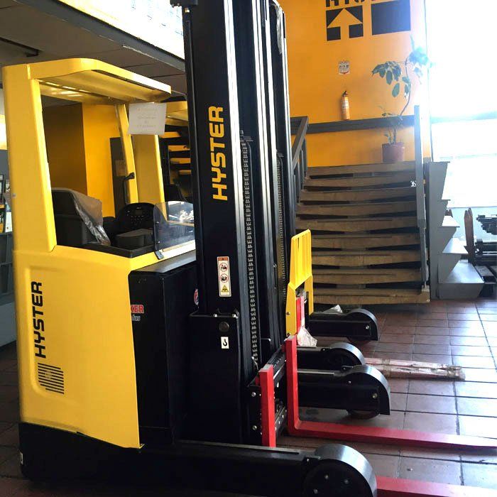 Una carretilla elevadora Hyster amarilla y negra está estacionada frente a las escaleras
