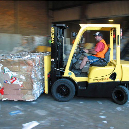 Un hombre conduce una carretilla elevadora Hyster amarilla.