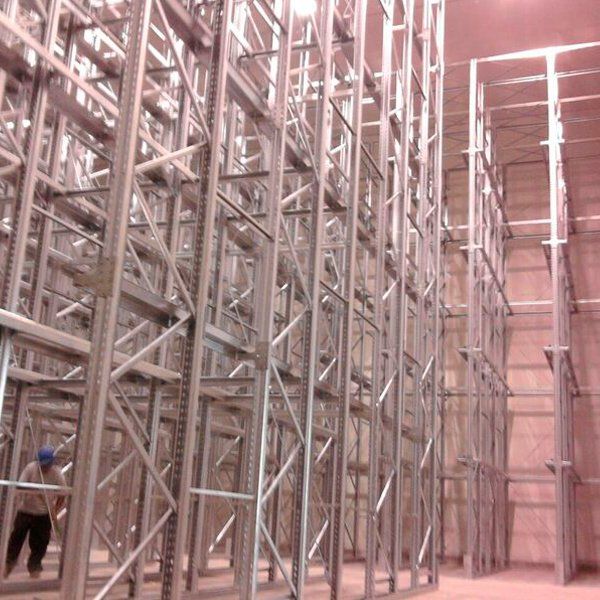 Un hombre camina por un almacén con muchos estantes.