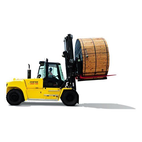 Una carretilla elevadora amarilla lleva un gran carrete de madera sobre un fondo blanco.
