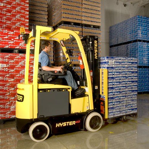 Un hombre conduce una carretilla elevadora Hyster en un almacén.
