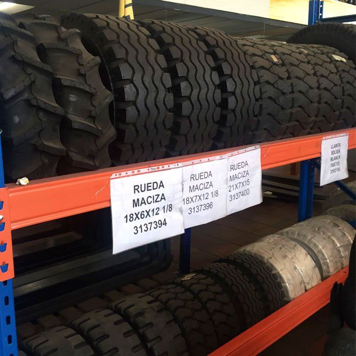 Un montón de llantas en un estante con un cartel que dice rueda