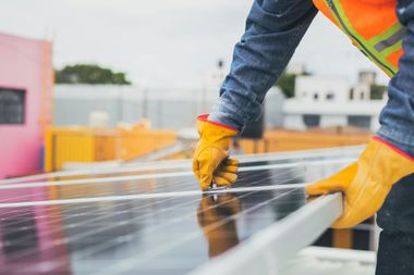 Worker in yellow gloves installing clear roofing panels on a construction site