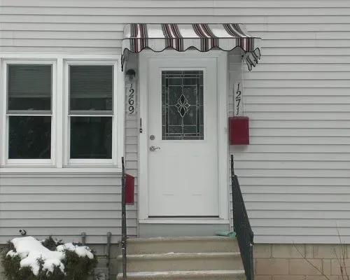 A white house with a striped awning over the front door