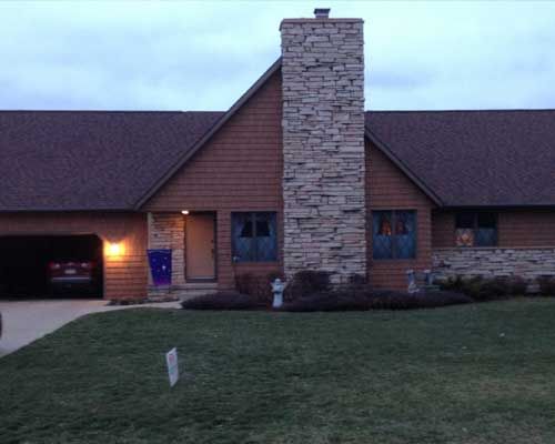 A house with a large stone chimney in front of it