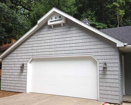 A garage with a white door and a roof that looks like a robot.